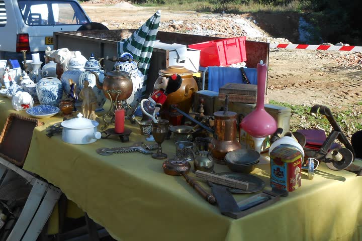 A yard-sale table covered in second-hand vases, copper pots and china