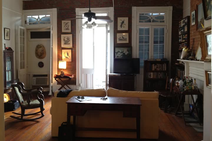 A lived-in living room with a sofa, rocking chair, TV and bookshelves