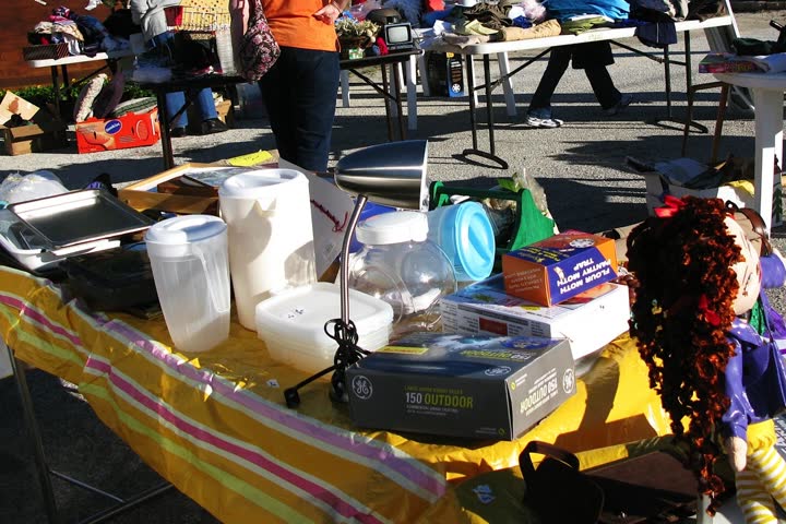 A community yard-sale table with jugs, a lamp and boxes